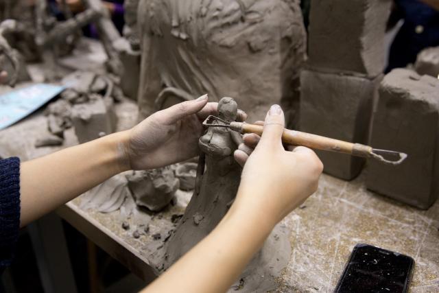 Hand using tool to create clay sculpture